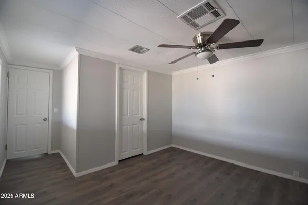 an empty room with wooden floor and fan