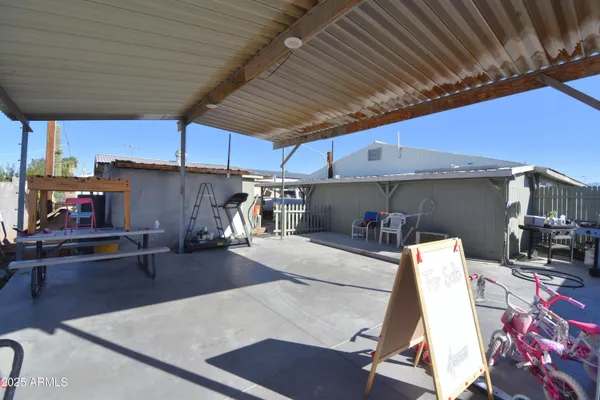 a view of a patio with table and chairs under an umbrella with a barbeque