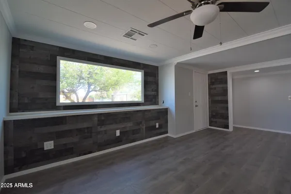a view of an empty room with a window and wooden floor