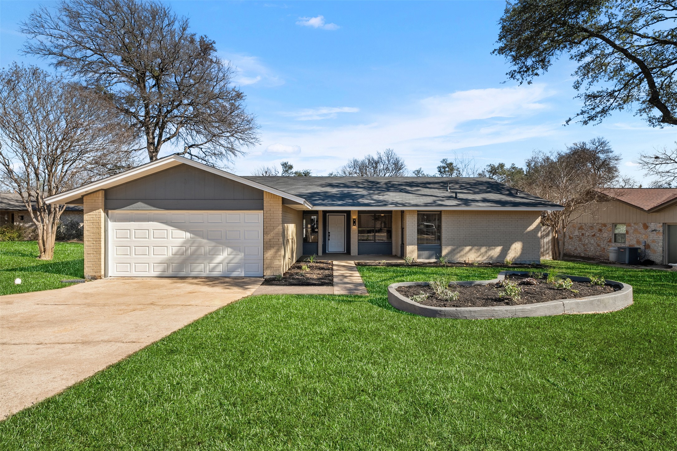 Ranch-style home featuring brick siding, driveway, and a front yard