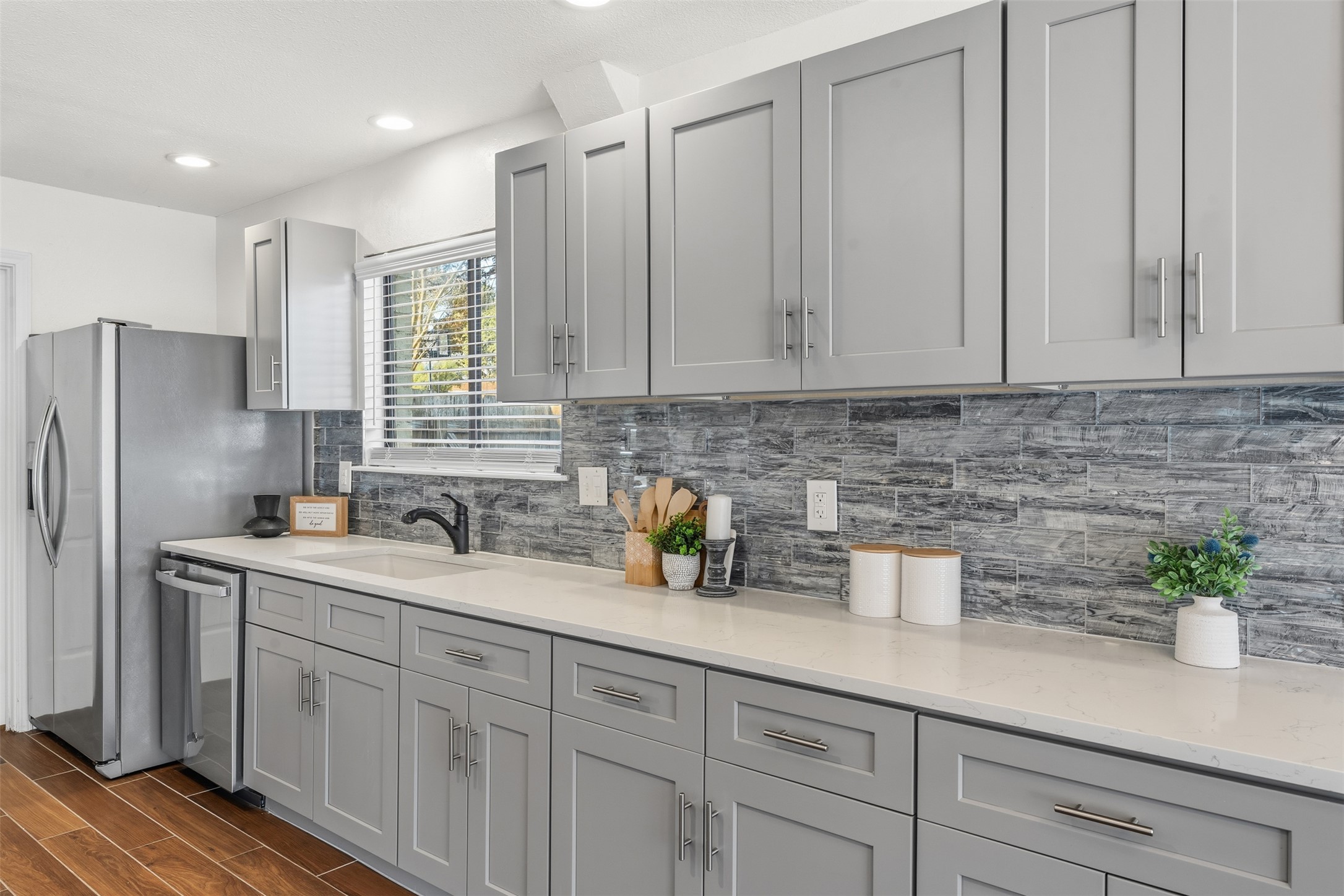 12401 Rusted Nail Cove Austin, TX 78750 - Photo 15 of 34 Kitchen featuring gray cabinetry, backsplash, wood tiled floors, light stone counters, and recessed lighting
