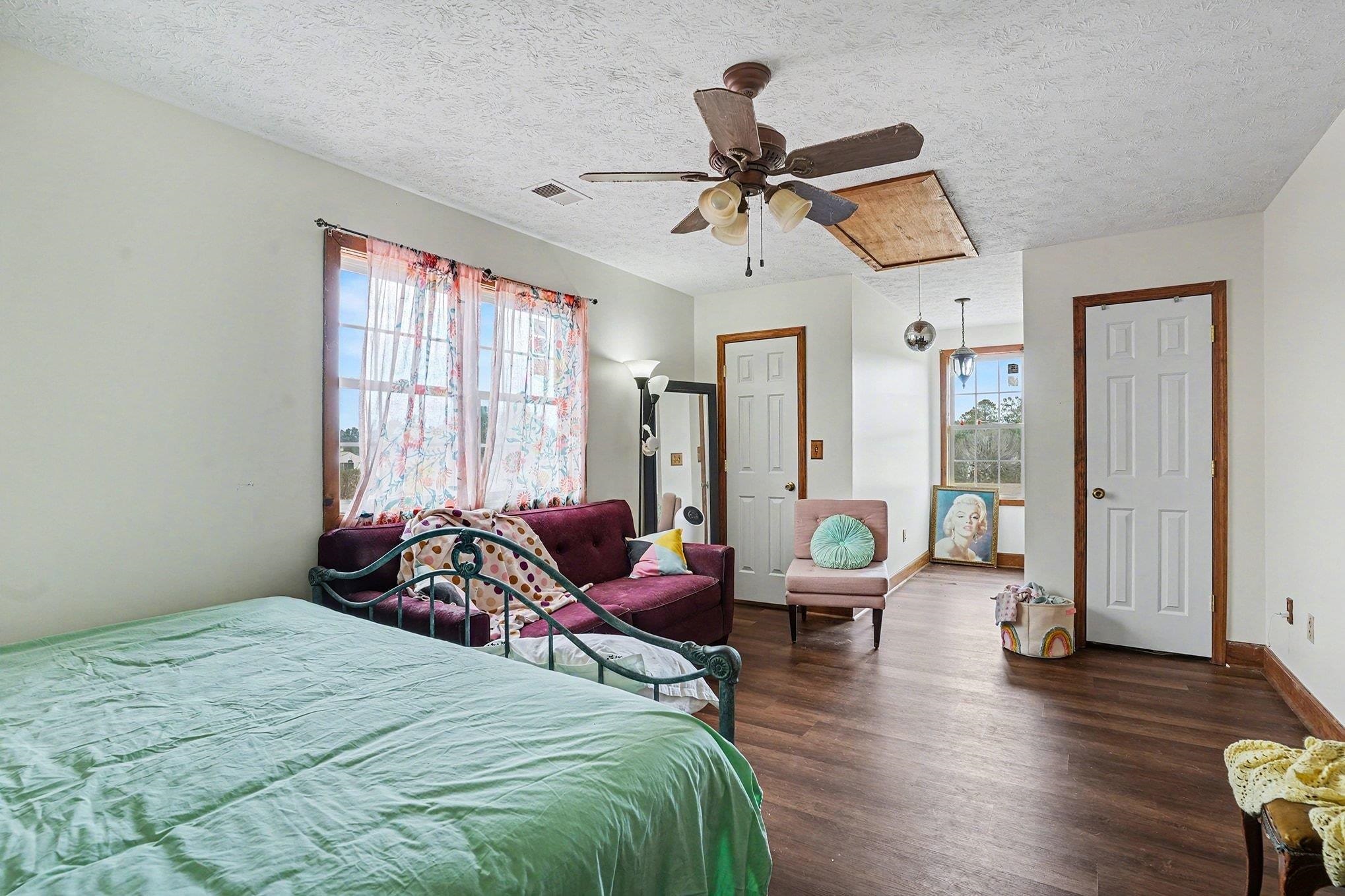 202 Highway 747 Loris Sc 29569 Loris, SC 29569 - Photo 22 of 34 Bedroom featuring attic access, multiple windows, dark wood finished floors, a textured ceiling, and a ceiling fan