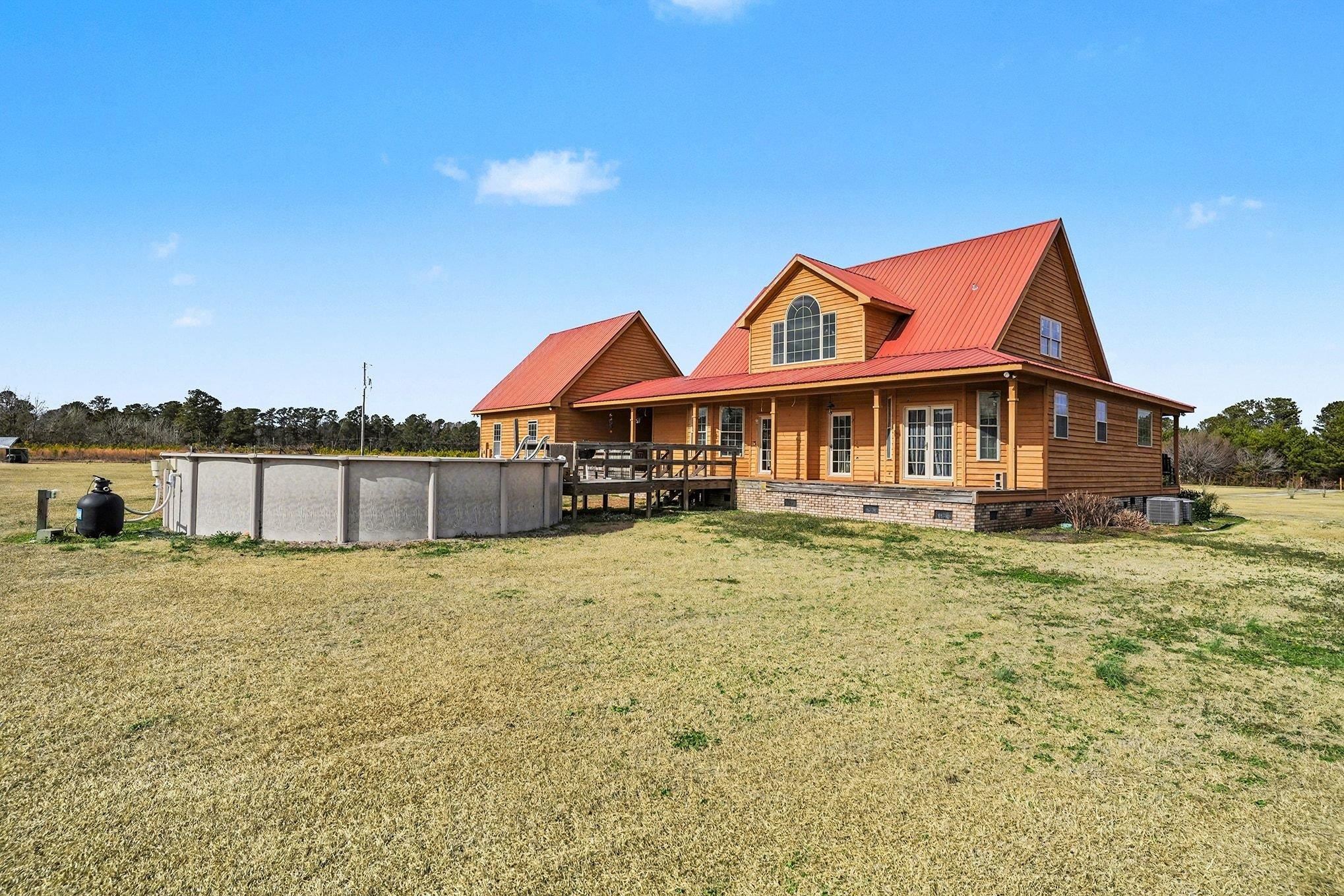 202 Highway 747 Loris Sc 29569 Loris, SC 29569 - Photo 25 of 34 Rear view of home featuring a huge back yard, crawl space, an outdoor pool, covered porch, and a metal roof