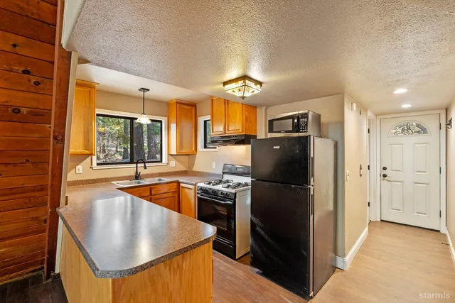 a kitchen with stainless steel appliances granite countertop a refrigerator a sink a stove and a refrigerator