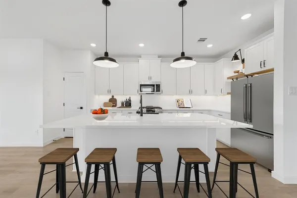 a kitchen with stainless steel appliances a dining table chairs and white cabinets