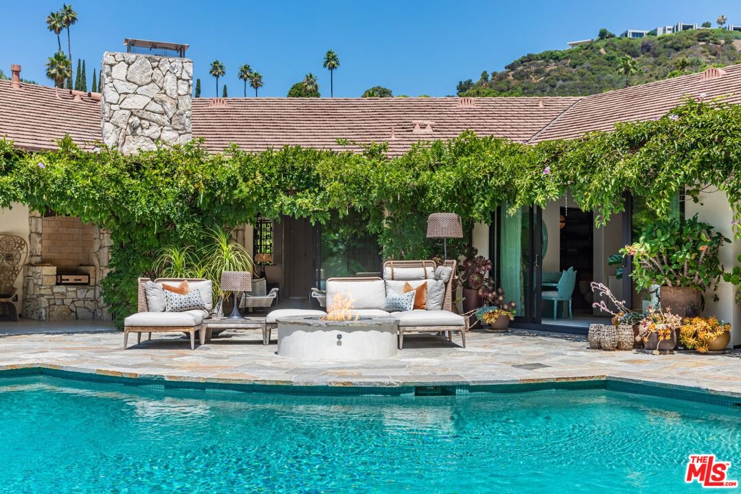1070 North Hillcrest Road Beverly Hills, CA 90210 - Photo 24 of 29 a view of a patio with table and chairs potted plants and a palm tree