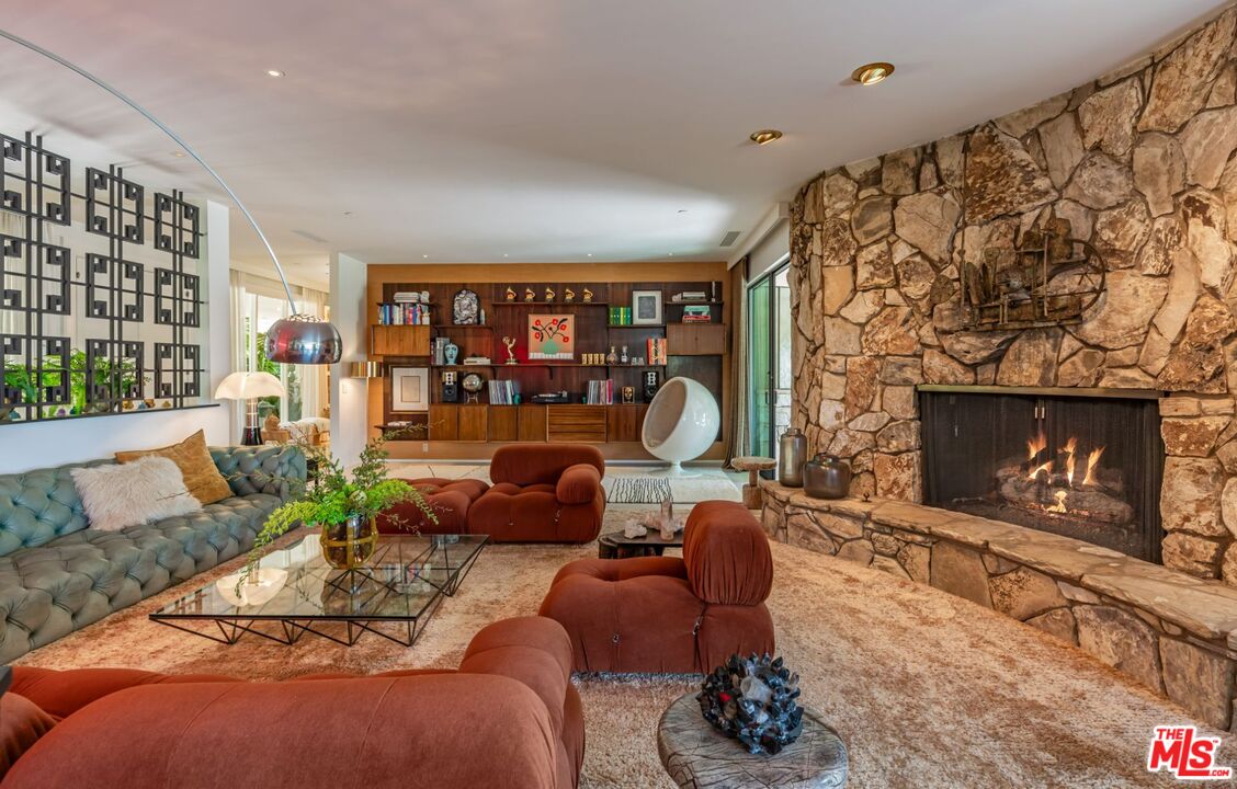 1070 North Hillcrest Road Beverly Hills, CA 90210 - Photo 6 of 29 a living room with furniture a fireplace and a floor to ceiling window