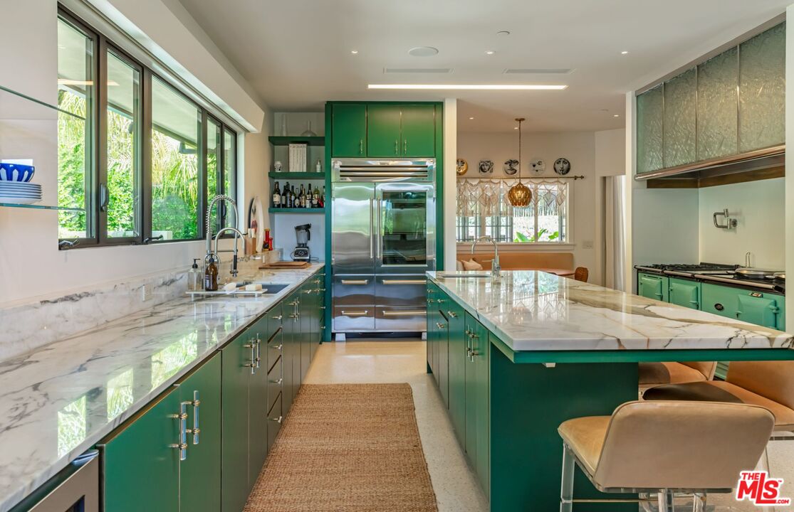 1070 North Hillcrest Road Beverly Hills, CA 90210 - Photo 9 of 29 a kitchen with stainless steel appliances kitchen island granite countertop a sink and a stove