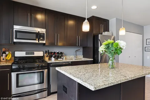 a kitchen with stainless steel appliances kitchen island granite countertop wooden cabinets and a stove