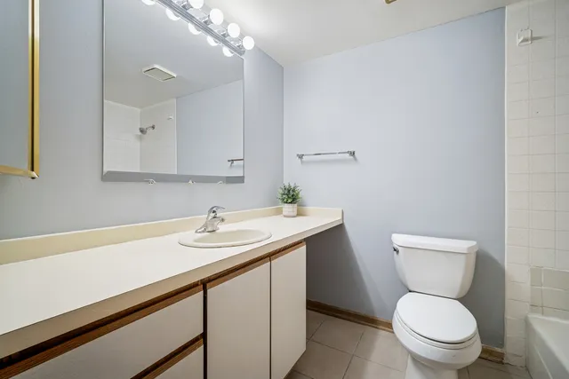 a bathroom with a granite countertop toilet sink and mirror