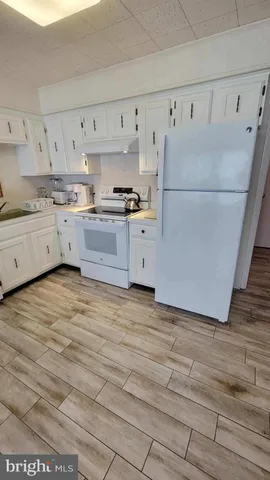a kitchen with granite countertop a refrigerator and white cabinets