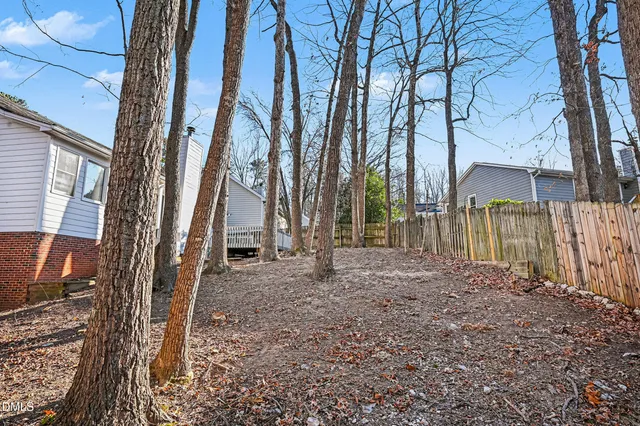 a view of a backyard with large trees and wooden fence