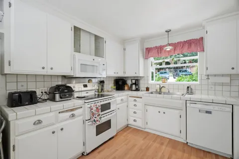 a kitchen with white cabinets and white appliances