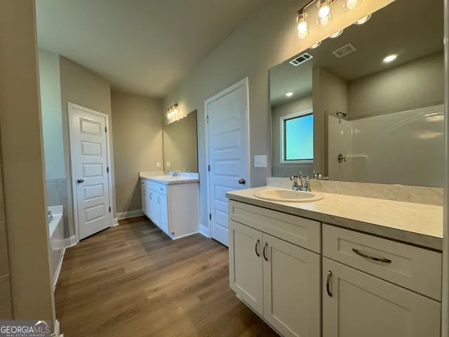 a bathroom with a double vanity sink a mirror and a shower