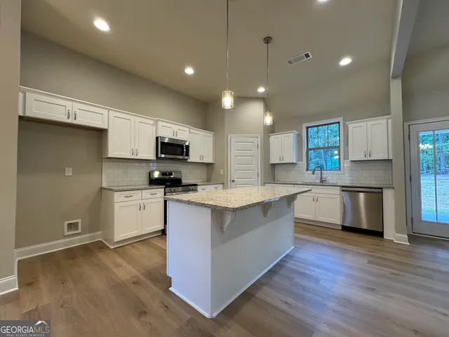a large kitchen with stainless steel appliances granite countertop a stove a sink dishwasher a microwave oven and a refrigerator with wooden floor