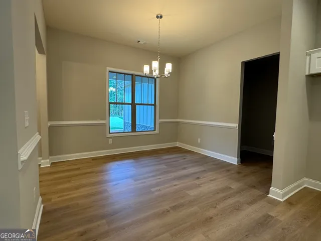 an empty room with wooden floor chandelier and windows