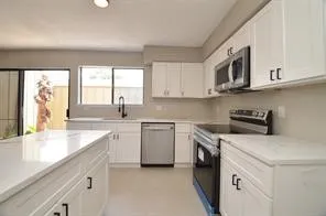 a kitchen with stainless steel appliances granite countertop white cabinets a sink and a stove