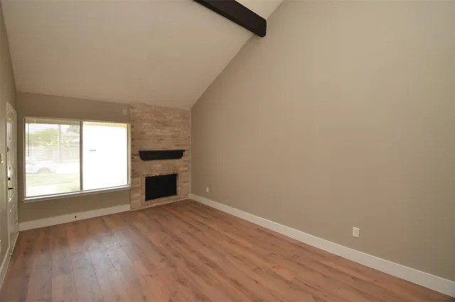a view of an empty room with a window and wooden floor