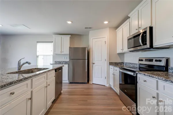 a kitchen with stainless steel appliances granite countertop a refrigerator stove microwave and sink