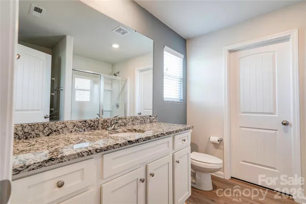 a bathroom with a granite countertop sink a toilet and a window