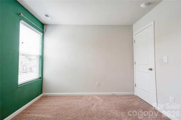 a view of an empty room with window and stairs