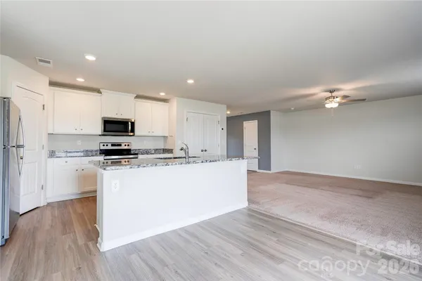a view of kitchen with granite countertop cabinets and refrigerator