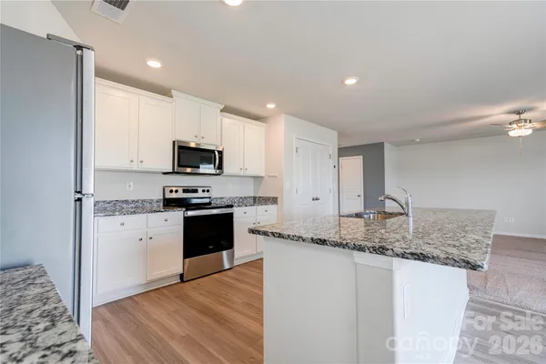 a kitchen with granite countertop a stove sink and microwave