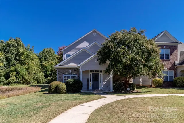 a view of a house with a yard and large tree