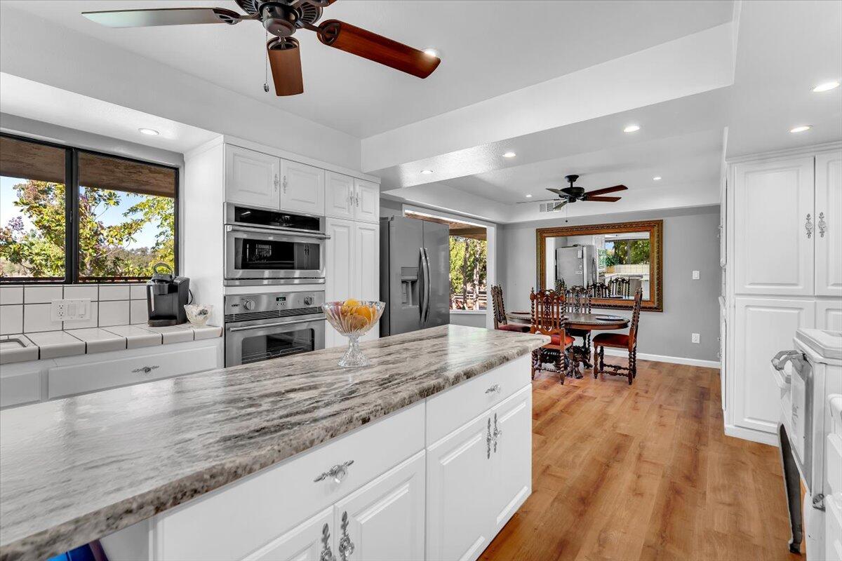 5521 Churn Crk Road Redding, CA 96002 - Photo 37 of 154 a kitchen with granite countertop a stove a sink a dining table and chairs with wooden floor