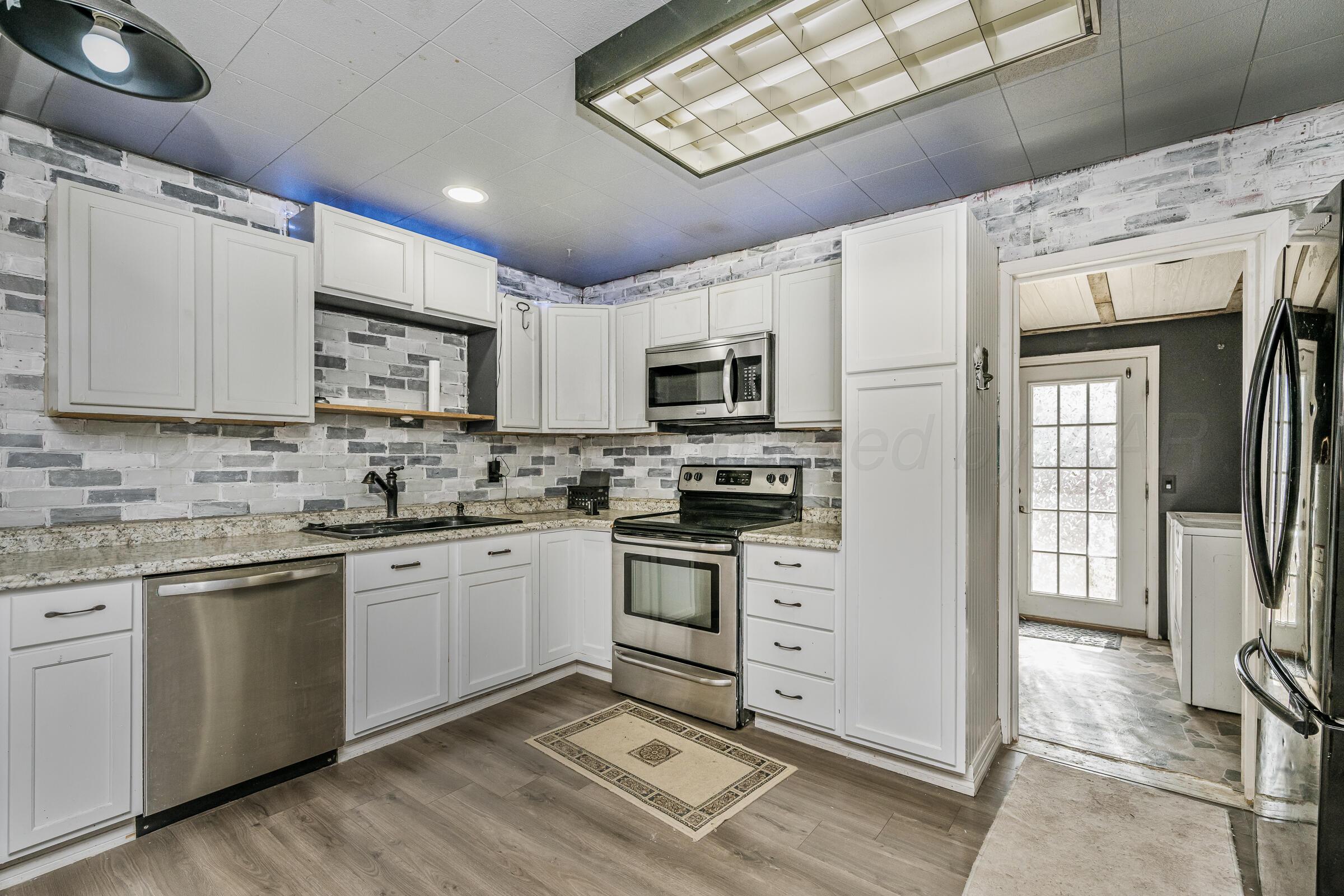4429 Bowie Street Amarillo, TX 79110 - Photo 8 of 20 a kitchen with stainless steel appliances granite countertop a stove sink and microwave