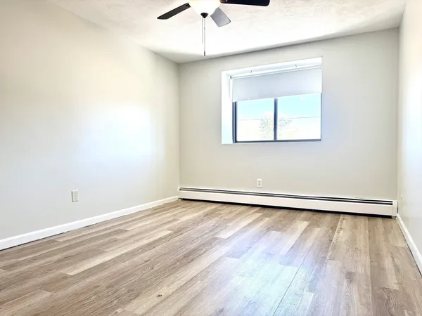 a view of an empty room with wooden floor and a window