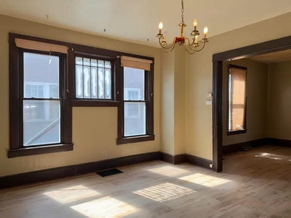 a view of an empty room with window and chandelier