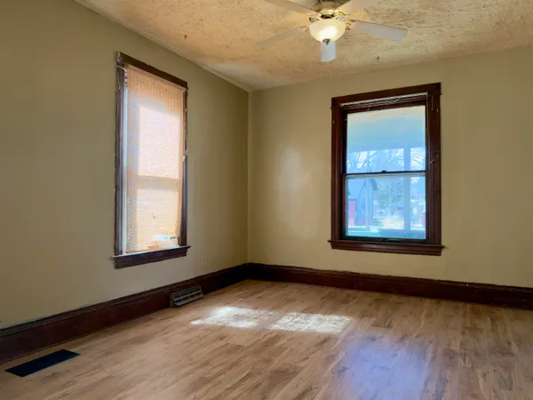an empty room with a window and wooden floor
