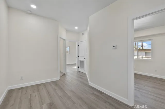 a view of a hallway with wooden floor and a bathroom