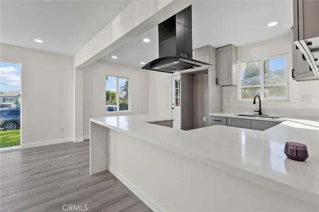 a large kitchen with stainless steel appliances a large counter top a sink a stove a refrigerator and a window