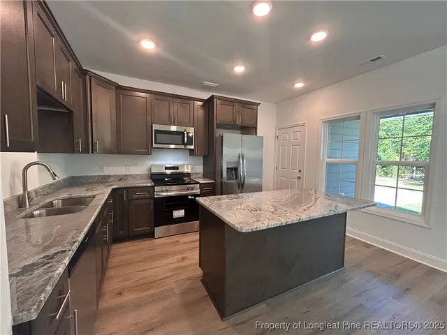 a kitchen with stainless steel appliances granite countertop wooden cabinets a sink dishwasher a stove and a refrigerator