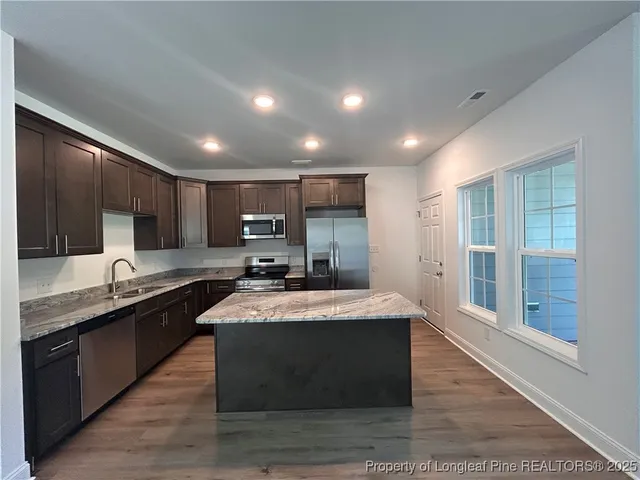 a large kitchen with kitchen island a sink stainless steel appliances and cabinets