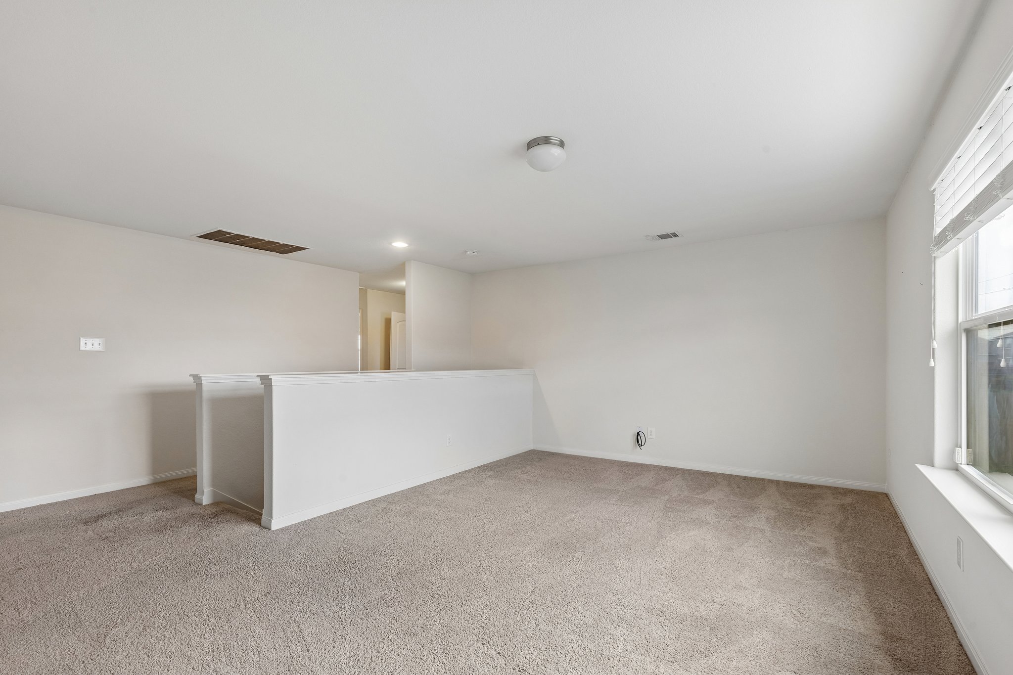 704 Cleary Lane Jarrell, TX 76537 - Photo 12 of 25 Carpeted loft area with a white half-wall railing, a window with blinds, and a flush-mount ceiling light fixture