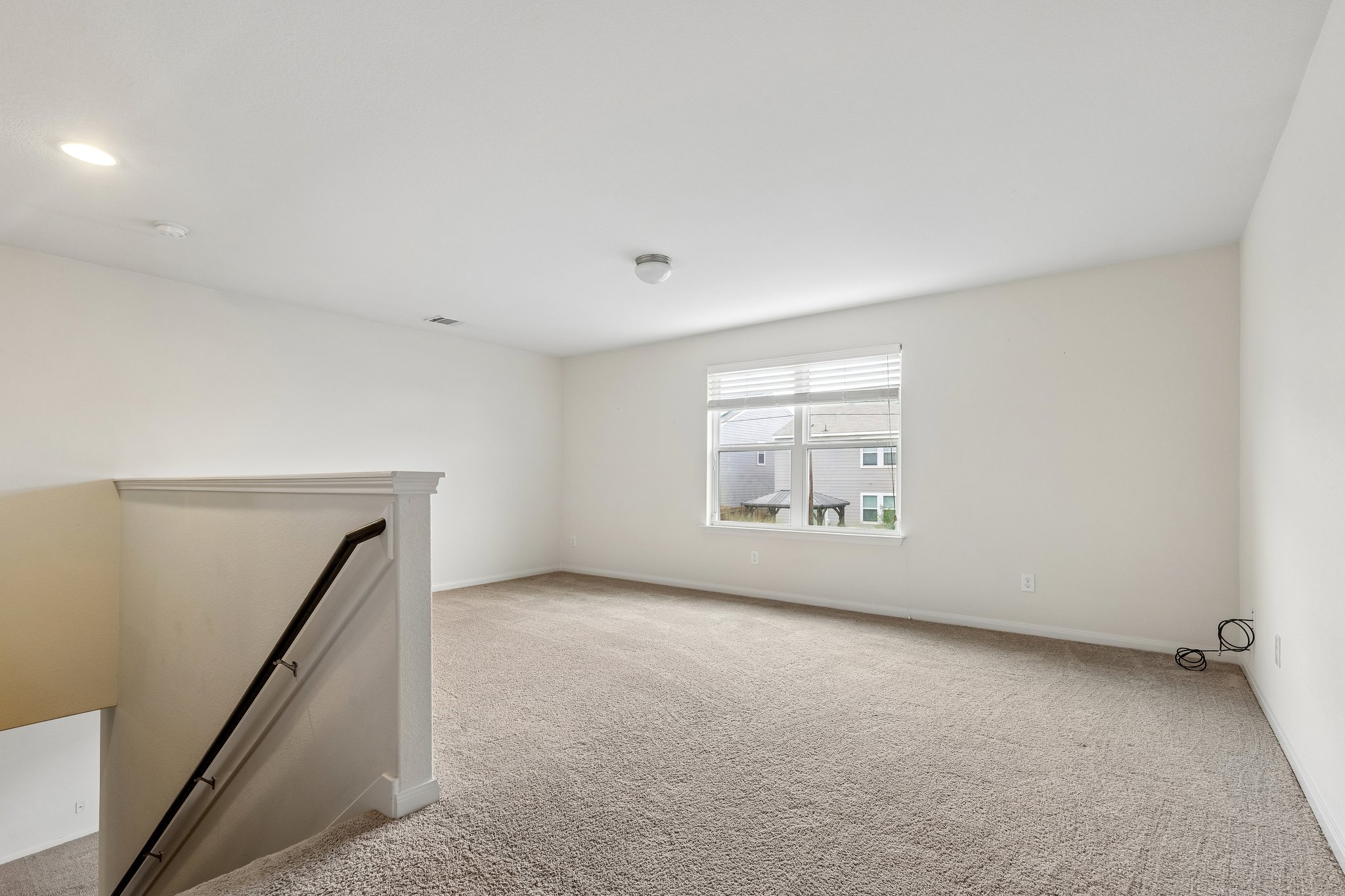 704 Cleary Lane Jarrell, TX 76537 - Photo 13 of 25 Spacious carpeted room featuring a large window with blinds, recessed ceiling lighting, and a neutral color palette