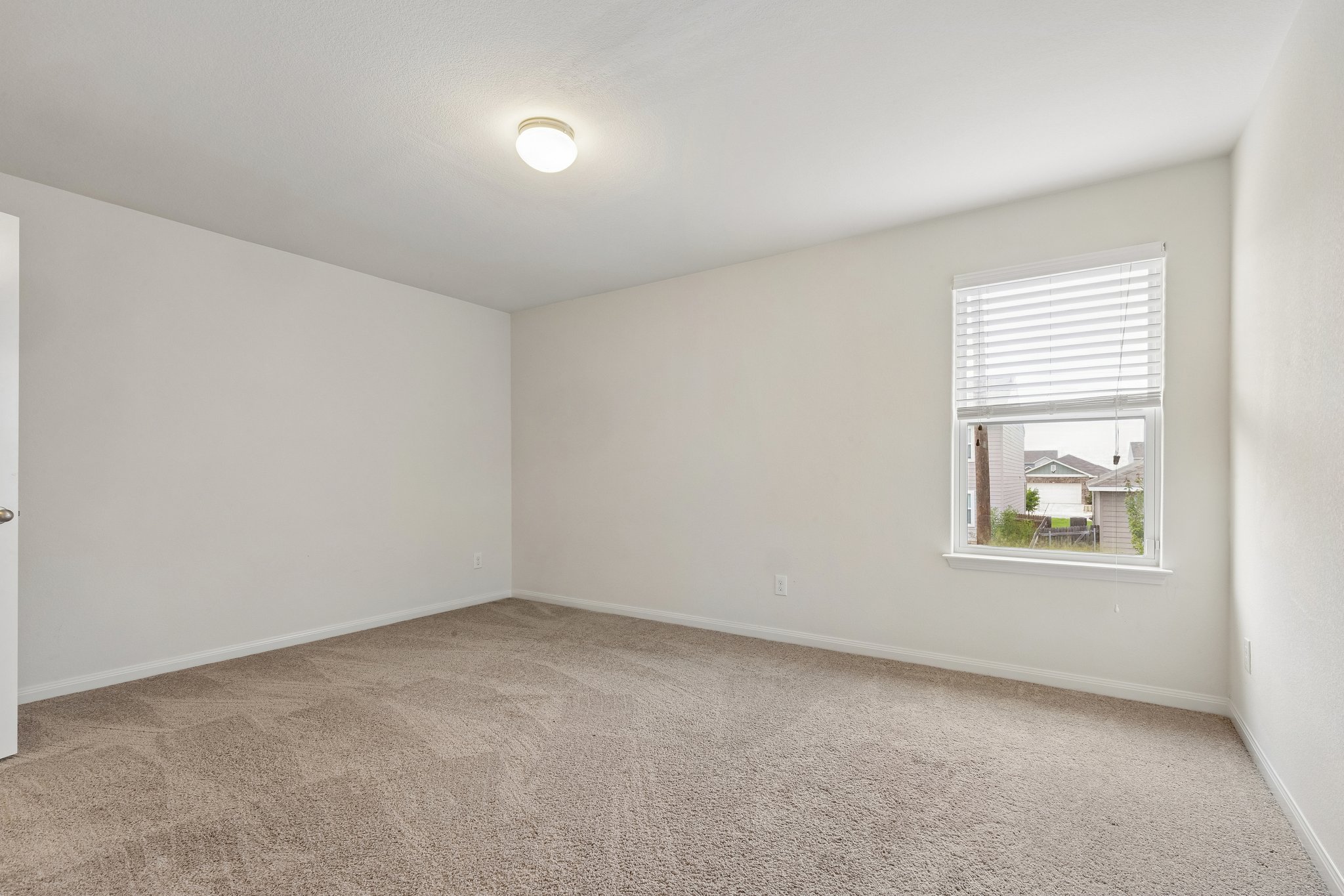 704 Cleary Lane Jarrell, TX 76537 - Photo 14 of 25 Carpeted interior room featuring a window with blinds, white walls, and a ceiling-mounted light fixture