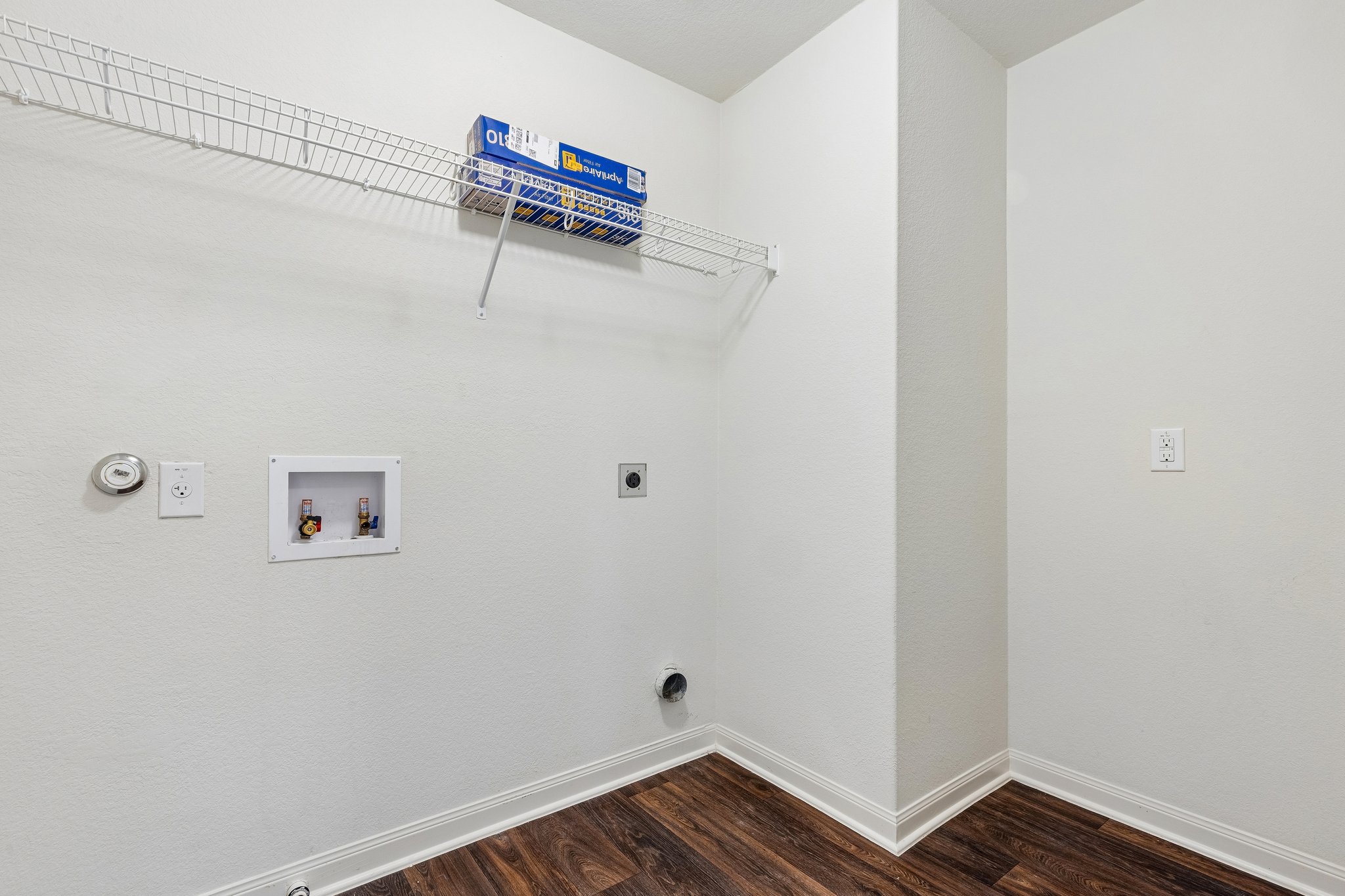 704 Cleary Lane Jarrell, TX 76537 - Photo 16 of 25 Dedicated utility space featuring wood-finish flooring, crisp white walls, white baseboards, and a built-in wire shelving unit