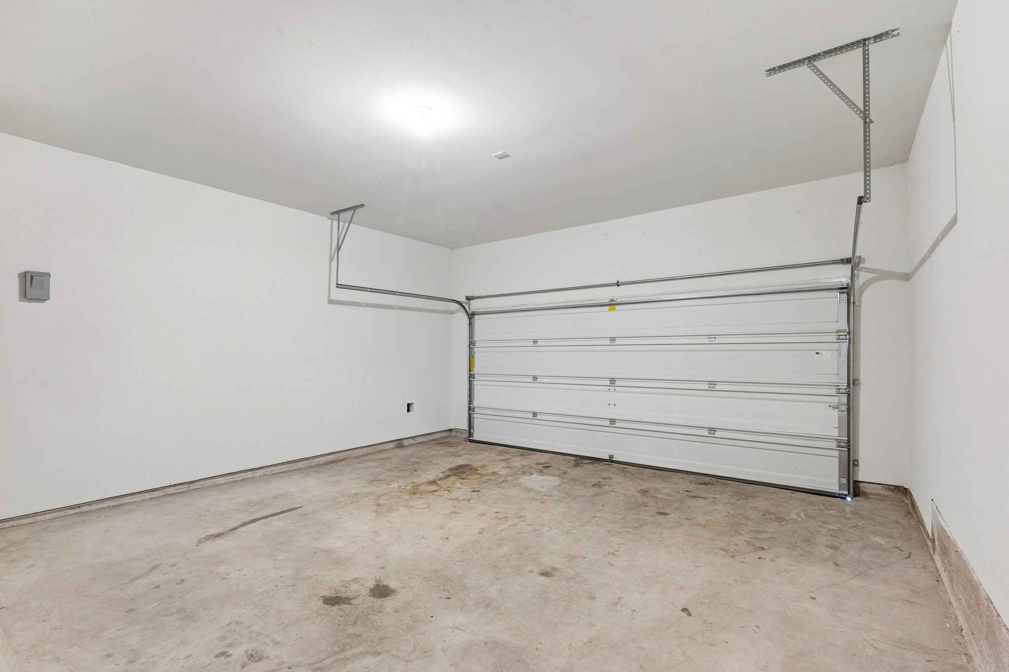 704 Cleary Lane Jarrell, TX 76537 - Photo 23 of 25 Garage featuring a sectional overhead door, painted drywall, concrete flooring, and an overhead light fixture