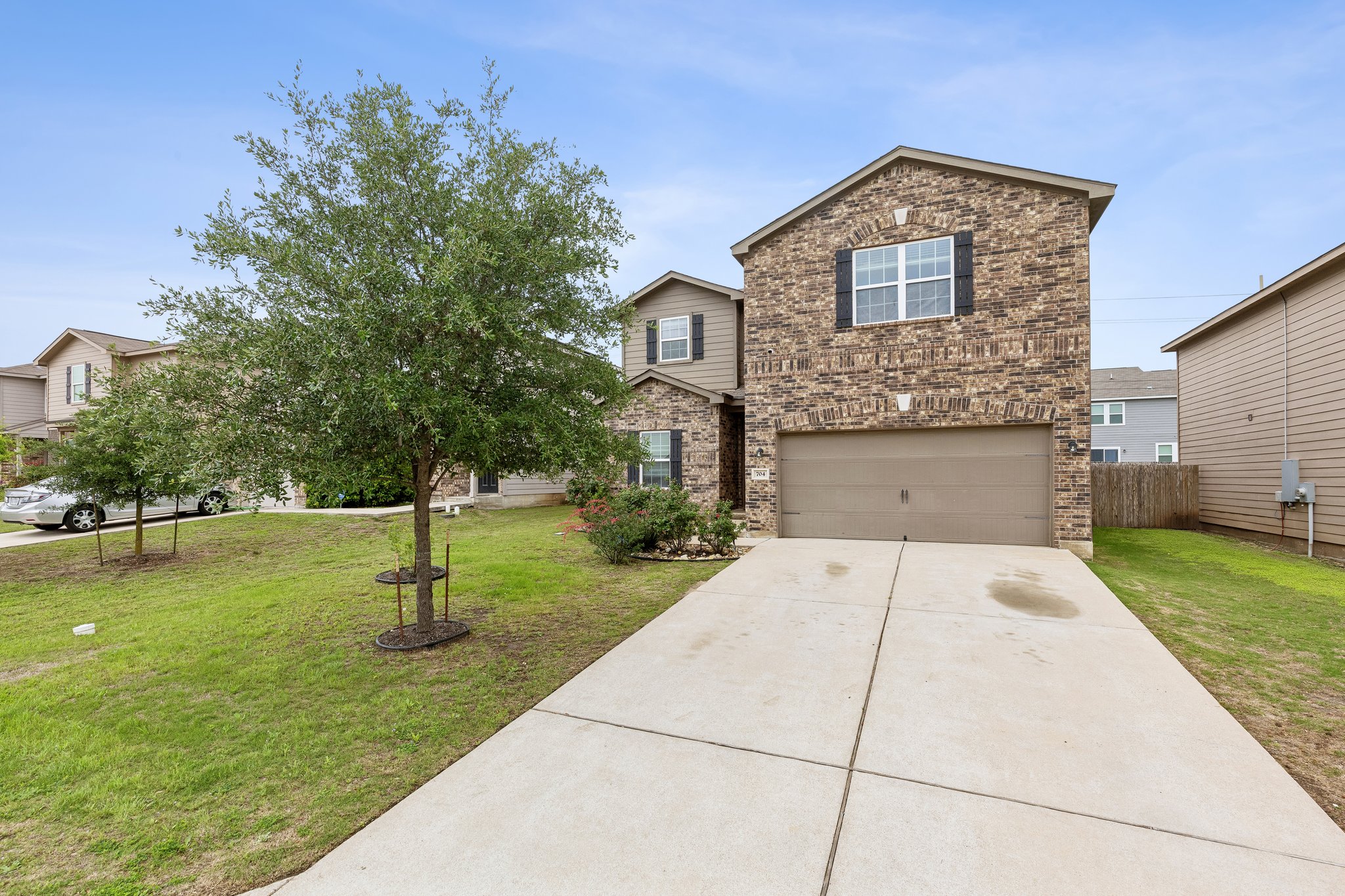 704 Cleary Lane Jarrell, TX 76537 - Photo 24 of 25 Brick facade with contrasting dark shutters, a two-car garage, and a concrete driveway