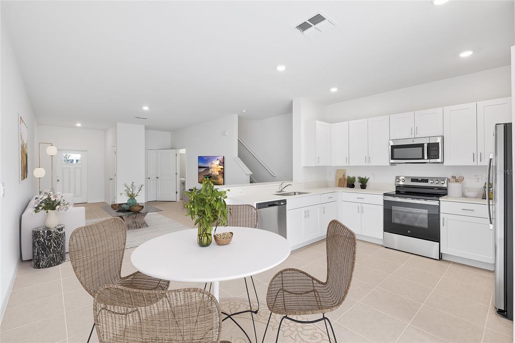36148 Risa Michele Street Zephyrhills, FL 33541 - Photo 12 of 34 a kitchen with stainless steel appliances kitchen island granite countertop a stove a sink a dining table and chairs