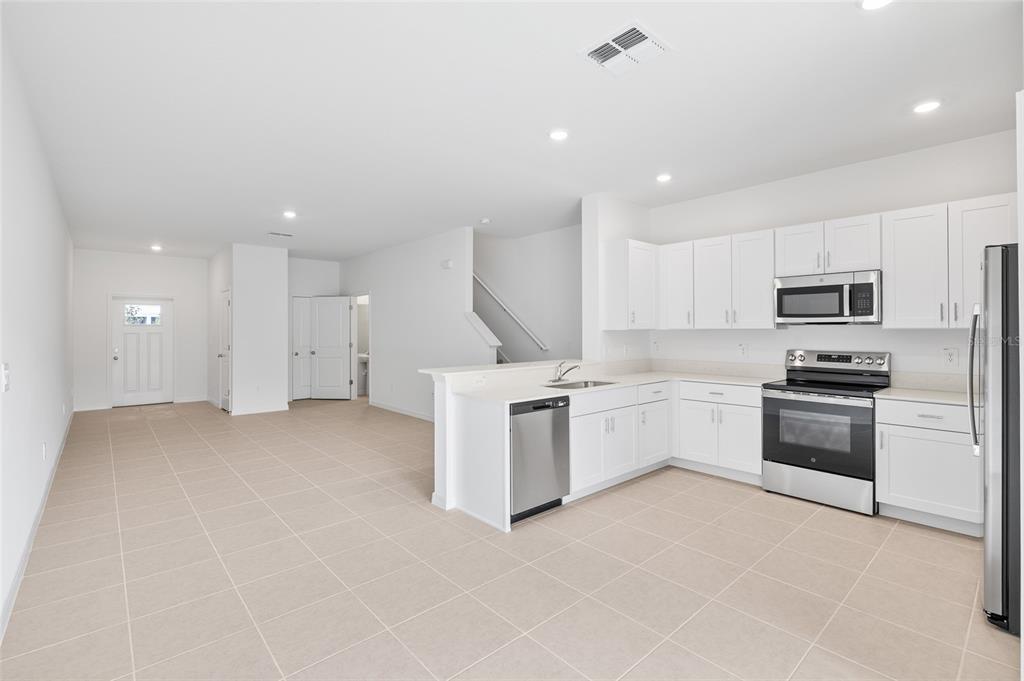 36148 Risa Michele Street Zephyrhills, FL 33541 - Photo 13 of 34 a kitchen with white cabinets and stainless steel appliances
