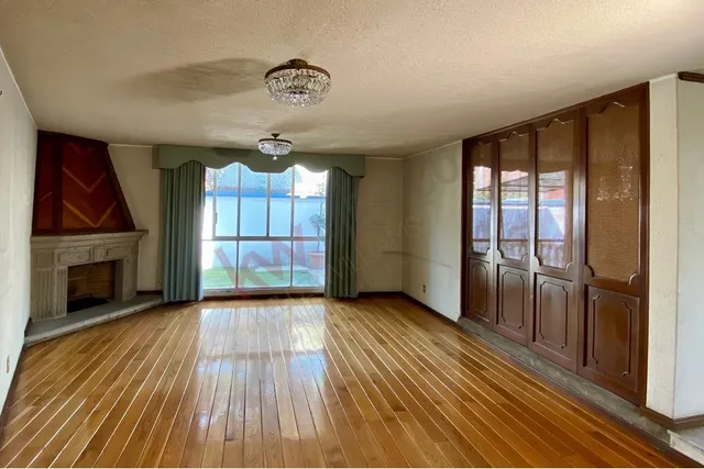 an empty room with wooden floor fireplace and windows