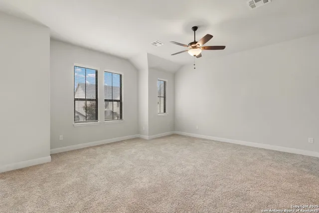 an empty room with windows and ceiling fan