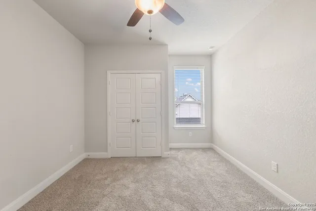 an empty room with a ceiling fan and a window