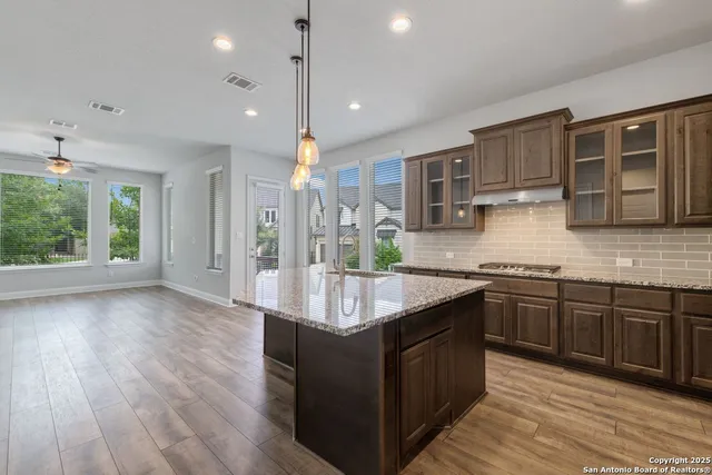 a kitchen with stainless steel appliances granite countertop a stove a sink dishwasher and a microwave oven with wooden floor