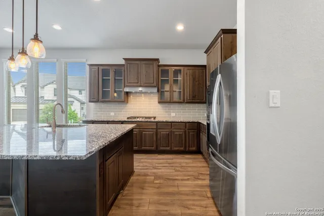 a kitchen with stainless steel appliances granite countertop a sink and wooden cabinets